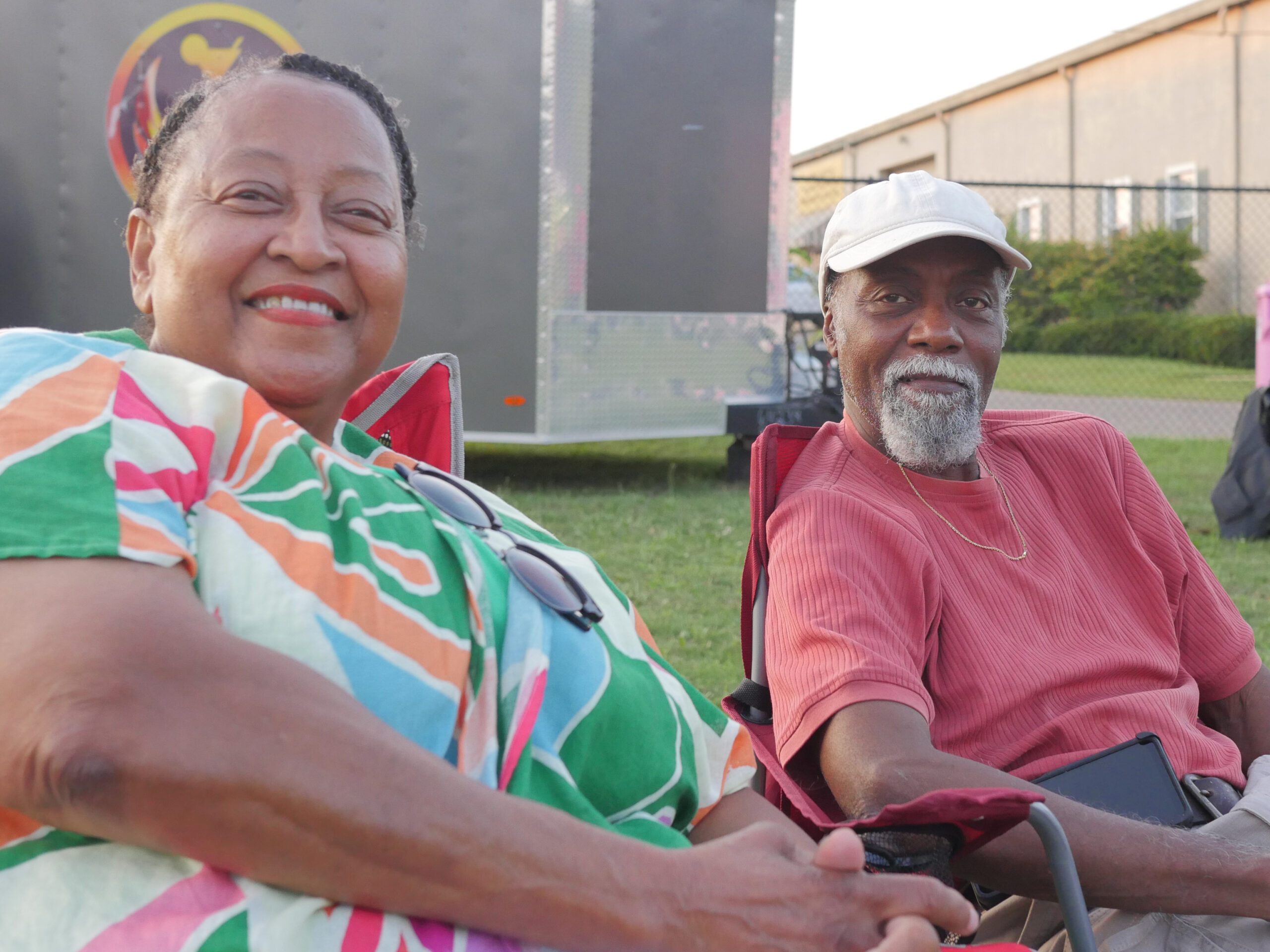 A man and woman sitting in lawn chairs smiling during the concert.